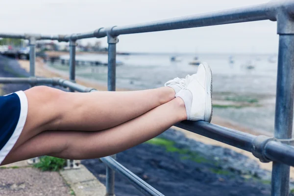 女人在海边栏杆上休息的脚 — 图库照片