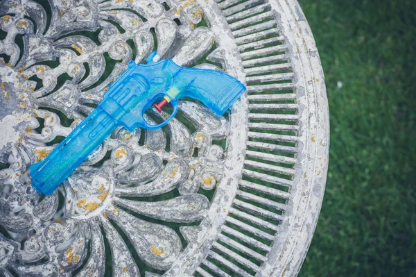 Pistola de agua azul en la mesa en el jardín — Foto de Stock