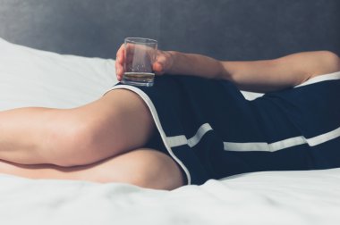 Genç kadın onun elinde cam ile yatakta yatarken