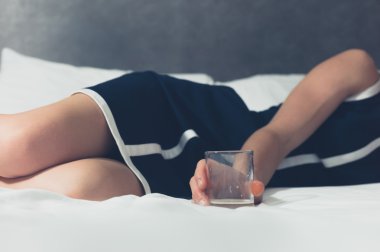 Genç kadın onun elinde cam ile yatakta yatarken