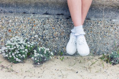 Denizin kenarında duvarda oturan kadın 