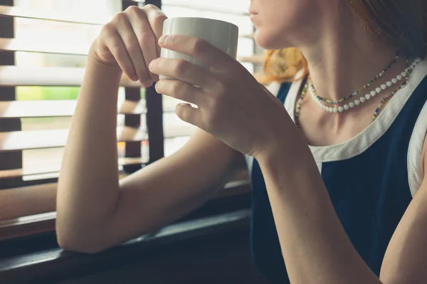 Kvinna med kaffe av fönstret i en diner — Stockfoto