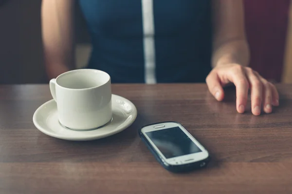 Frau im Abendessen mit Tasse und Smartphone — Stockfoto