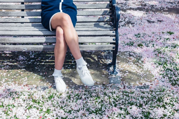 Женщина отдыхает на скамейке с цветущей вишней — стоковое фото