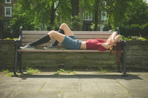 Jonge vrouw ontspannen op een bankje — Stockfoto