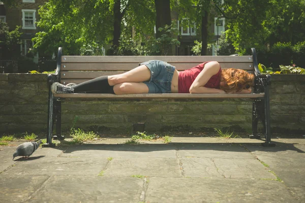 Молодая женщина отдыхает на скамейке в парке — стоковое фото