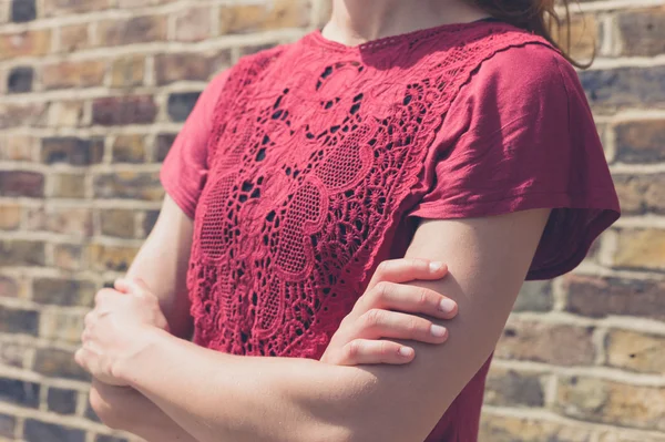 Jeune femme en haut rouge debout par un mur de briques — Photo