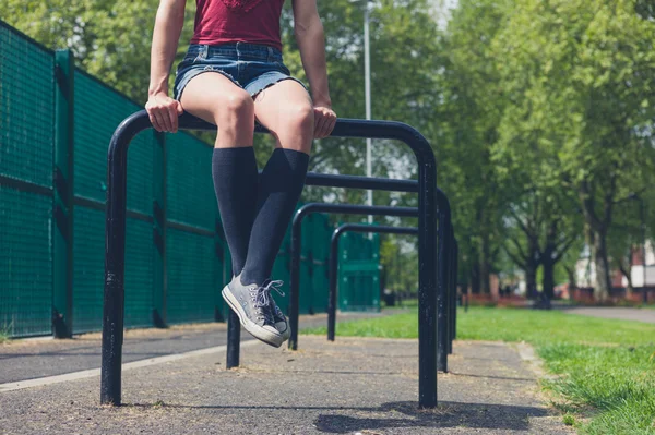 Ung kvinna sitter på en skena i park — Stockfoto