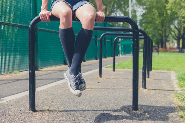 Jonge vrouw zitten op een rail in park — Stockfoto