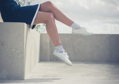 Beton duvara oturan genç kadın