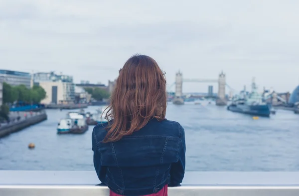 Young woman standing on a bridge and looking at city — Stock Photo, Image