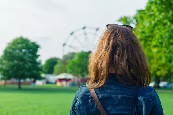 Žena v parku při pohledu na fun fair — Stock fotografie