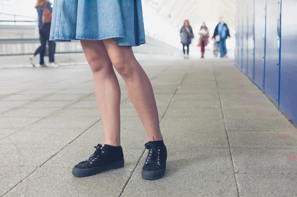 Jambes de jeune femme marchant dans la station — Photo