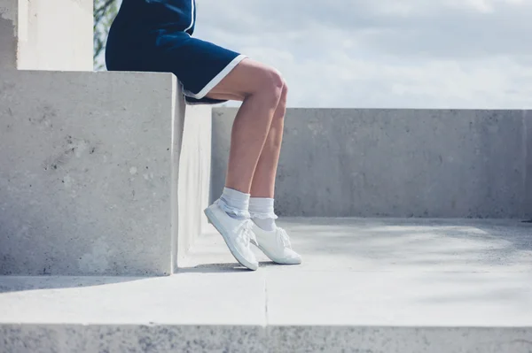 Młoda kobieta siedząca na betonową ścianę — Zdjęcie stockowe
