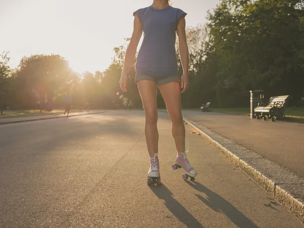 Mujer joven patinaje sobre ruedas en el parque al atardecer — Foto de Stock