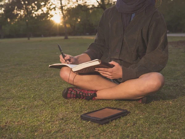 Vrouw op gras met Tablet PC en notebook in park — Stockfoto