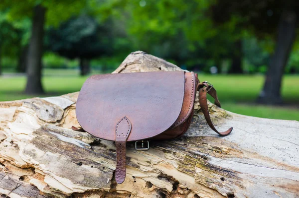 Leather handbag on tree trunk — Stock Photo, Image