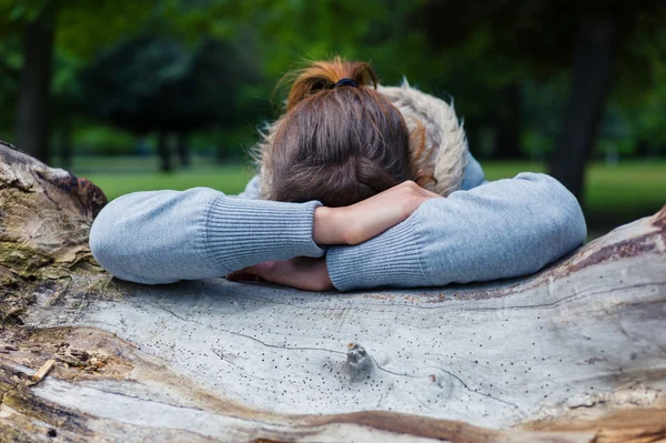 Sad woman resting on tree trunk — Stock Photo, Image