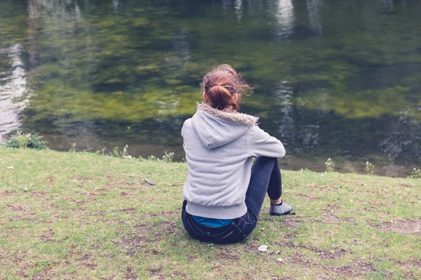Frau sitzt am Wasser im Park — Stockfoto