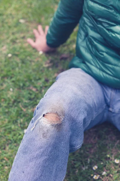 Человек в порванных джинсах на траве — стоковое фото