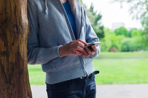 女性が公園で彼女のスマート フォンを使用して — ストック写真