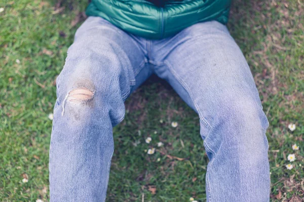 Uomo con jeans strappati sull'erba — Foto Stock