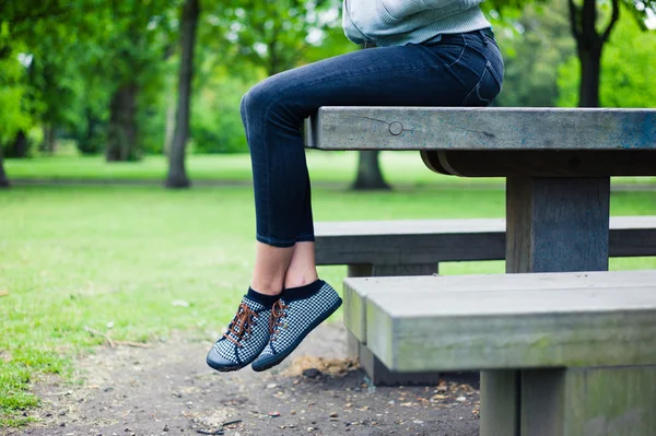 Kvinna sitter på bord i park — Stockfoto