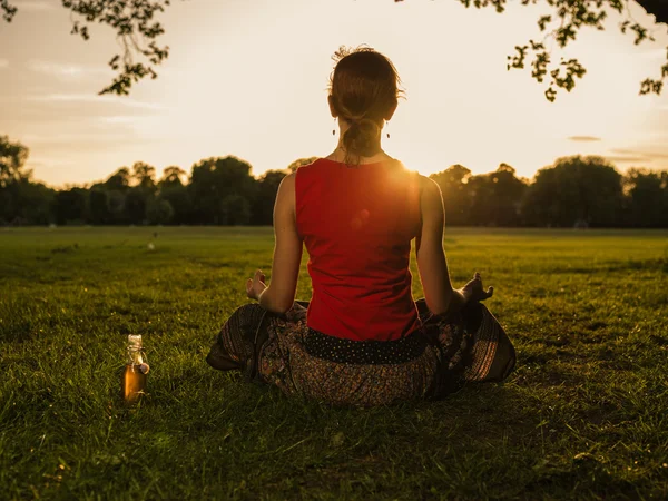 Mulher meditando no parque ao pôr do sol — Fotografia de Stock