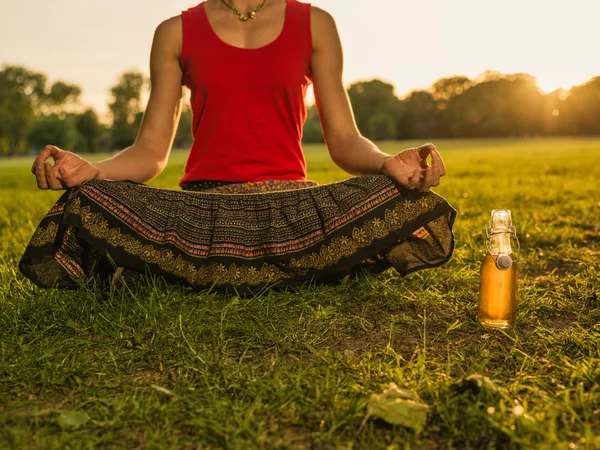 Kobieta medytacji w parku na zachodzie słońca — Zdjęcie stockowe