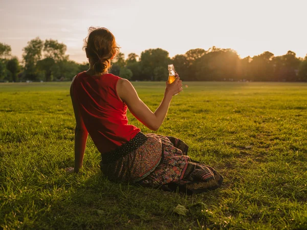 Vrouw drinken en zonsondergang bewonderen in park — Stockfoto