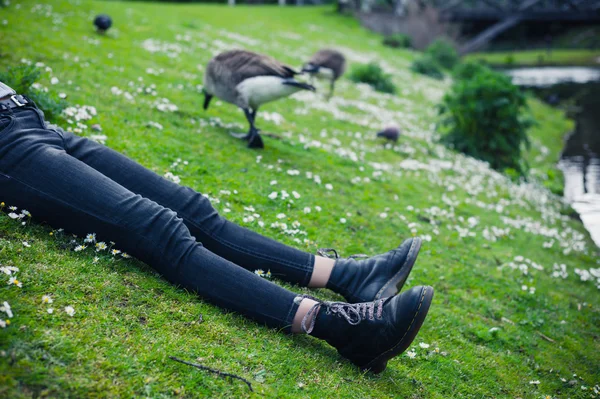 Jambes de jeune femme par l'eau dans le parc — Photo