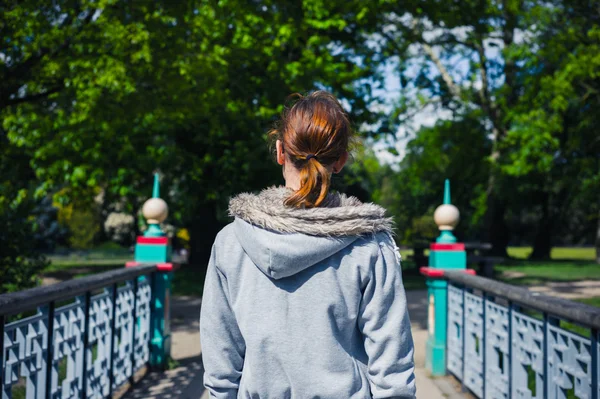 Mladá žena na mostě v parku — Stock fotografie