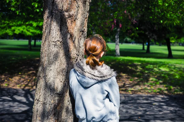 Giovane donna che riposa vicino all'albero nel parco — Foto Stock