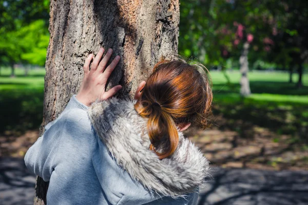 Vrouw verbergen achter boom in het park — Stockfoto