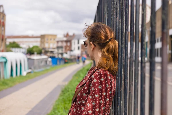 Mladá žena odpočívá plotu mimo — Stock fotografie