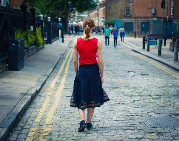Ung kvinna gå på kullerstensgata i sommar — Stockfoto