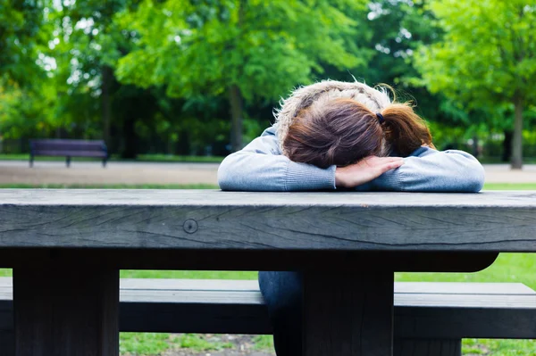 Smutný mladá žena u stolu v parku — Stock fotografie