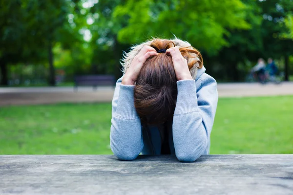 Sad young woman at table in park — Stock Photo, Image