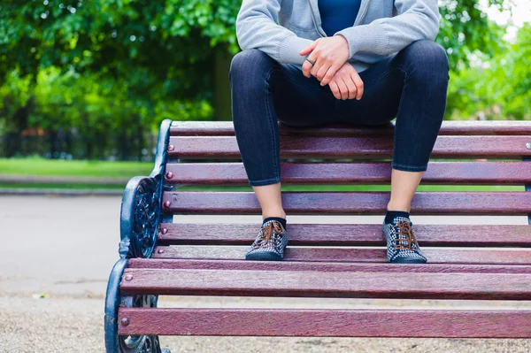 Jonge vrouw zit op een bankje in het park — Stockfoto