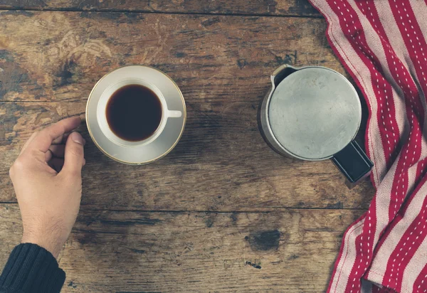 Hand met kop koffie op hout — Stockfoto