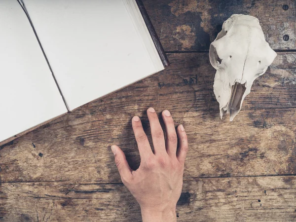 Cuaderno abierto en el escritorio con mano masculina y cráneo de oveja — Foto de Stock