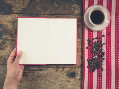 Fincan ve bir kitap tutan erkek el ile kahve kavramı