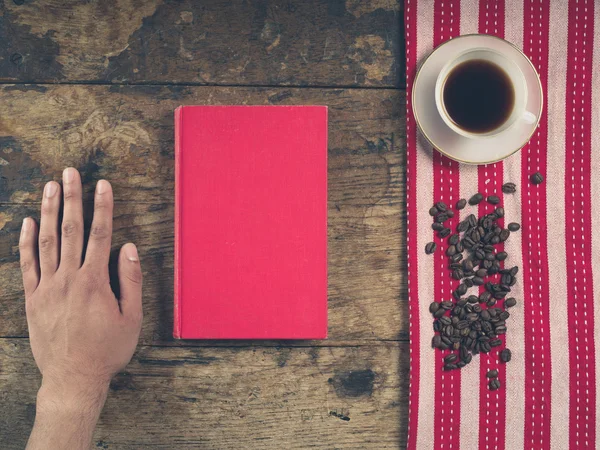 Kaffe konceptet med cup, en manlig hand och en bok — Stockfoto