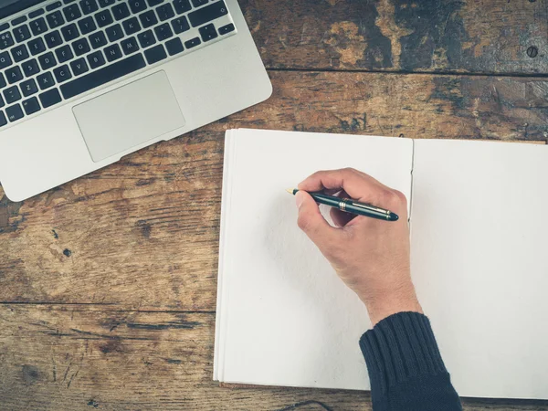 Handschrift im Notizblock per Laptop — Stockfoto