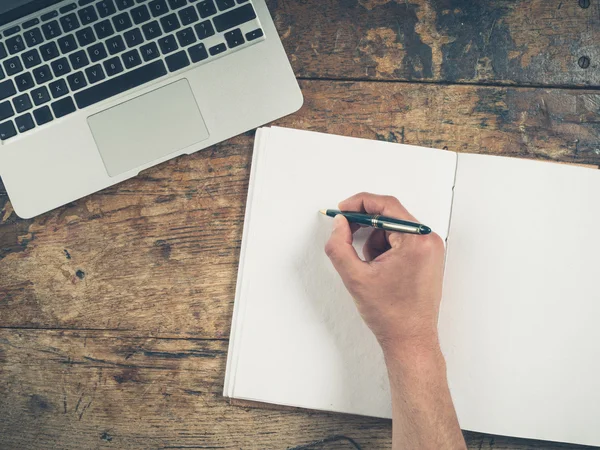 Hand schrijven in Kladblok door laptop — Stockfoto