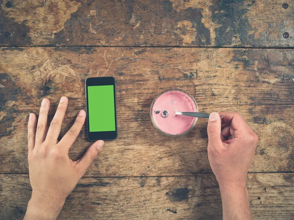 Мужская рука с помощью смартфона с йогуртом — стоковое фото