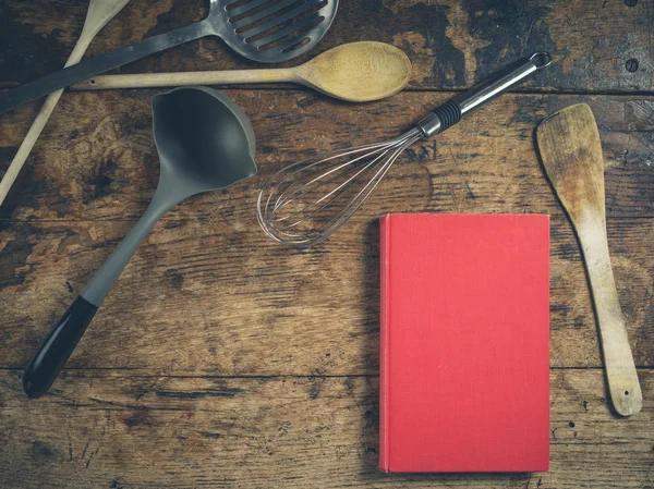 Keukengerei op houten tafel met boek — Stockfoto