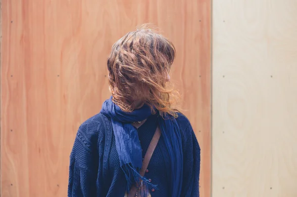 Jonge vrouw permanent door twee gekleurde houten muur — Stockfoto