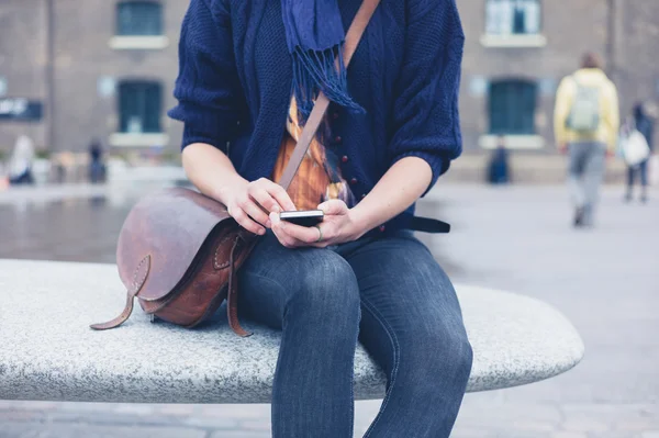 Mulher sentada no banco de granito usando telefone inteligente — Fotografia de Stock