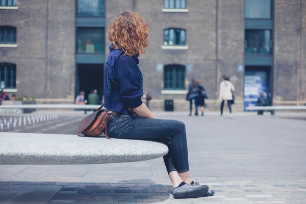 Jonge vrouw zittend op graniet bankje — Stockfoto